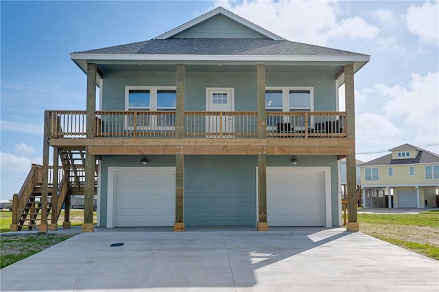 raised beach house with driveway, stairway, roof with shingles, and an attached garage