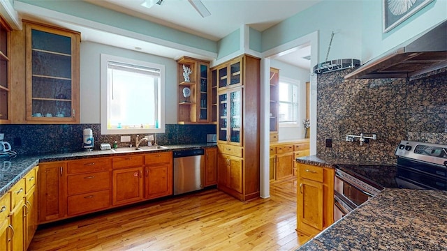 kitchen with tasteful backsplash, sink, dark stone countertops, stainless steel appliances, and light wood-type flooring