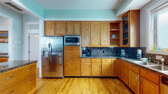 kitchen with stainless steel appliances, sink, light hardwood / wood-style flooring, and decorative backsplash