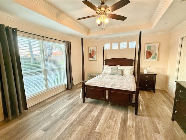 bedroom featuring ornamental molding, light hardwood / wood-style floors, ceiling fan, and a tray ceiling