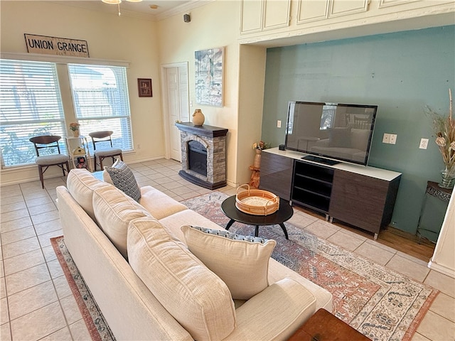 living room featuring ceiling fan, ornamental molding, a fireplace, and light tile patterned floors