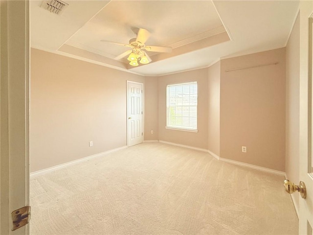 spare room with light colored carpet, a raised ceiling, ceiling fan, and ornamental molding