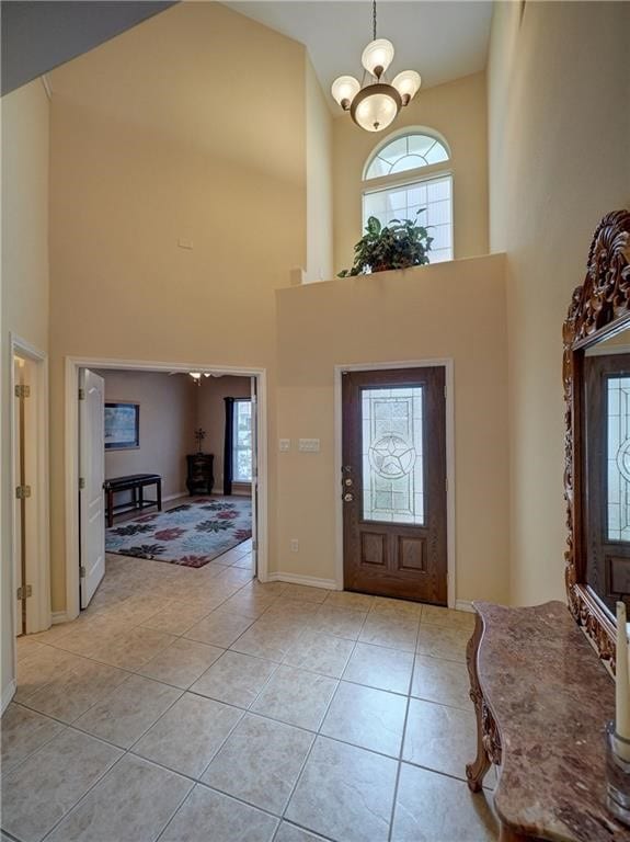 foyer entrance featuring light tile patterned flooring, a chandelier, and high vaulted ceiling