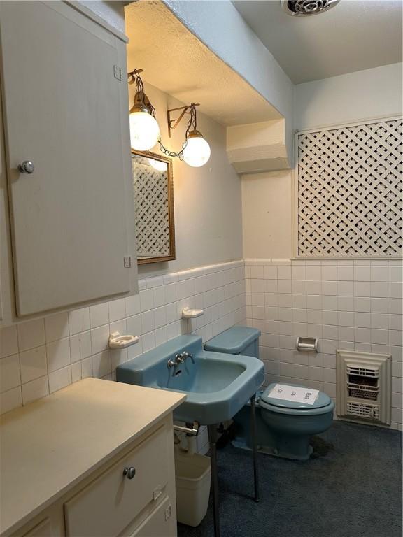 bathroom featuring tile walls, heating unit, and toilet