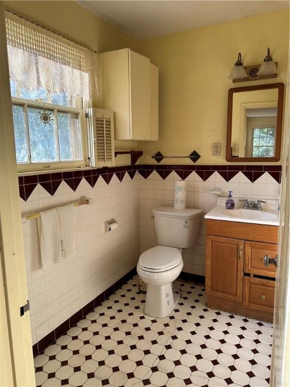 bathroom with tile walls, toilet, and vanity