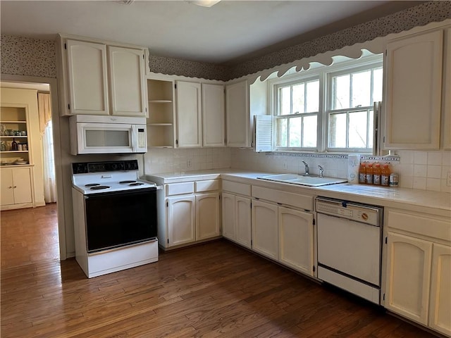 kitchen with sink, white appliances, white cabinets, and dark wood-type flooring