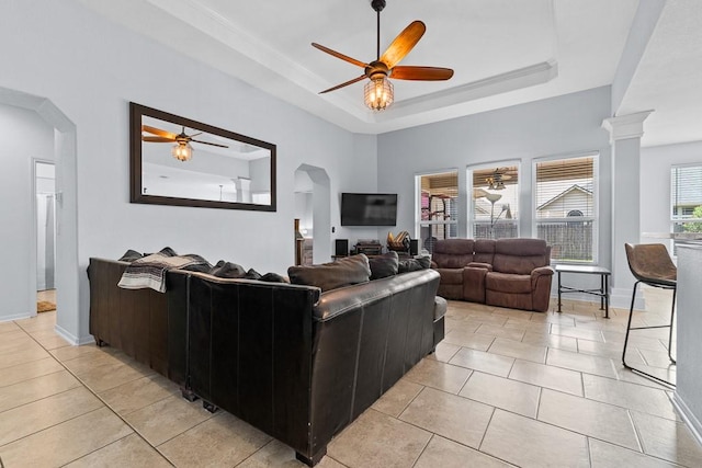 living area featuring light tile patterned floors, arched walkways, ceiling fan, and a raised ceiling