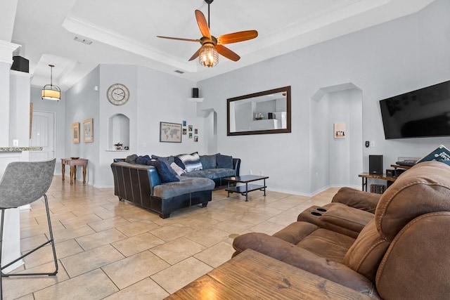 living area featuring ornamental molding, baseboards, ceiling fan, a tray ceiling, and light tile patterned floors