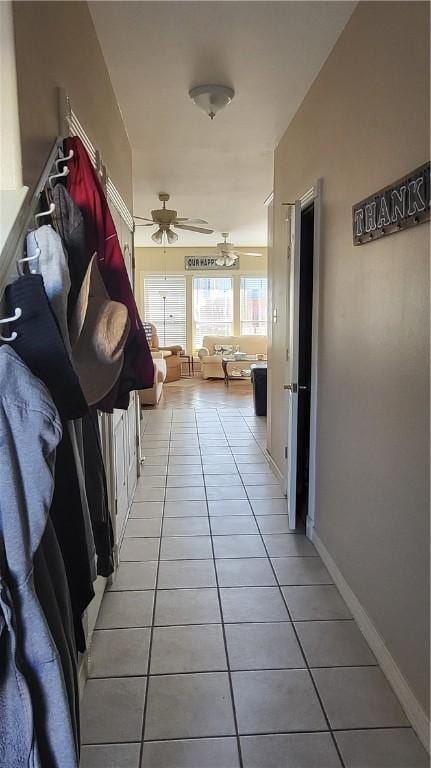 corridor with light tile patterned floors and baseboards