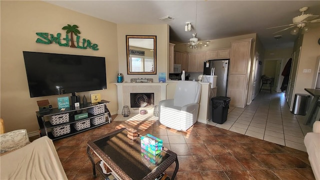 living area with tile patterned floors, visible vents, ceiling fan, and a fireplace