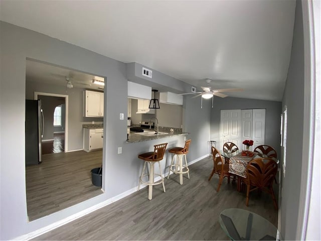 3321 Houston St, Corpus Christi, TX 78411 - kitchen featuring stainless steel appliances, wood finished floors, white cabinets, ceiling fan, and a peninsula