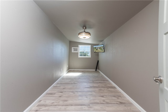 hallway featuring vaulted ceiling and light hardwood / wood-style flooring