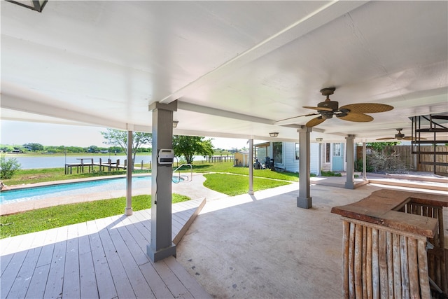 view of patio / terrace featuring a swimming pool side deck with water view and ceiling fan