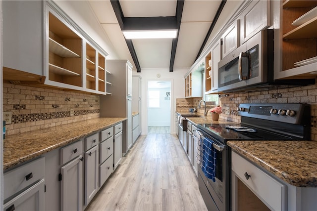 kitchen with light hardwood / wood-style floors, stainless steel appliances, stone counters, and backsplash