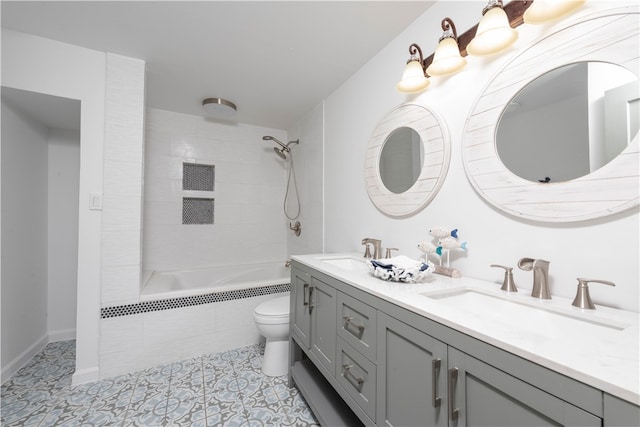 full bathroom with tile patterned flooring, vanity, tiled shower / bath combo, and toilet