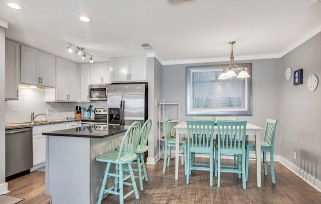 kitchen featuring a kitchen island, decorative light fixtures, decorative backsplash, stainless steel appliances, and dark wood-type flooring