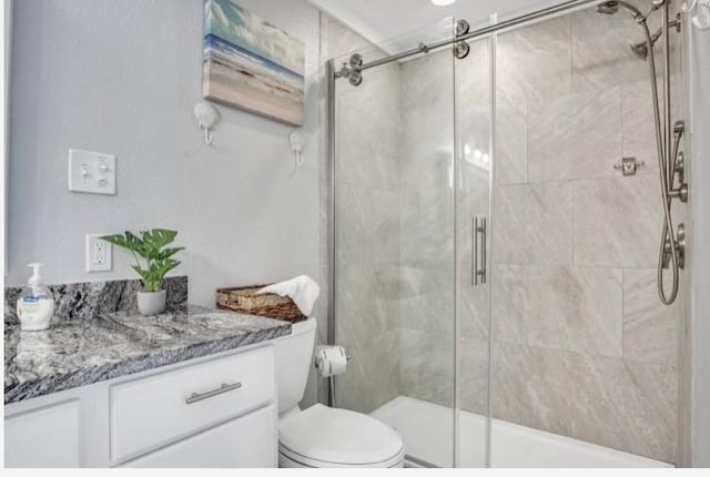 bathroom featuring vanity, toilet, and a shower with shower door