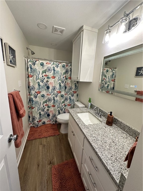 bathroom featuring hardwood / wood-style flooring, a textured ceiling, curtained shower, vanity, and toilet