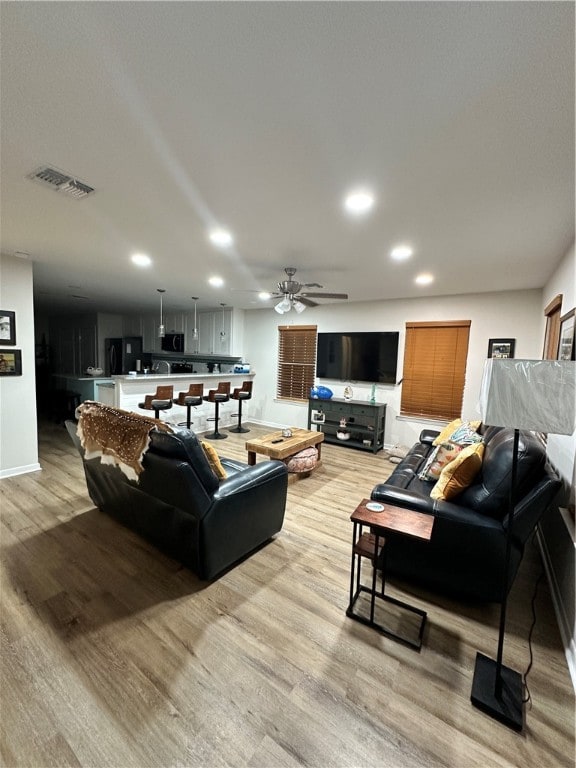 living room with light hardwood / wood-style floors and ceiling fan