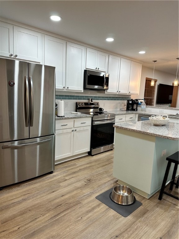 kitchen featuring pendant lighting, white cabinetry, kitchen peninsula, and stainless steel appliances