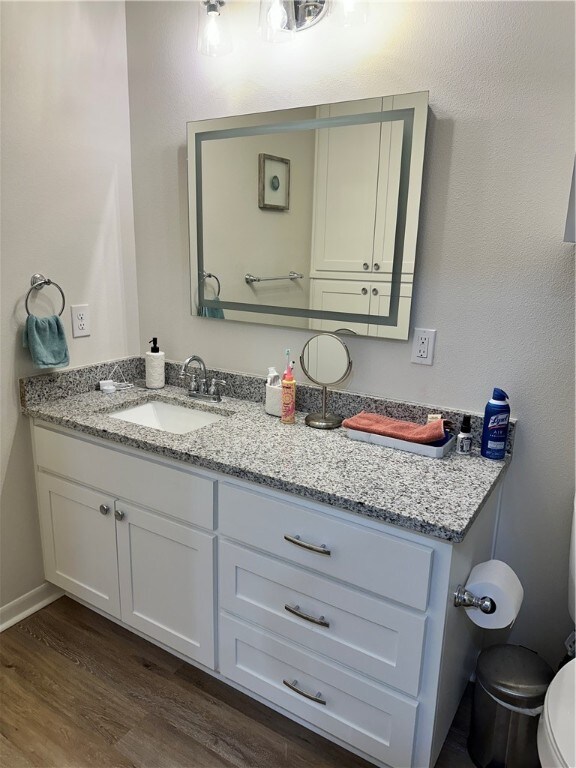 bathroom with toilet, vanity, and hardwood / wood-style floors