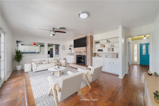 living room with ceiling fan, hardwood / wood-style floors, built in features, and a fireplace