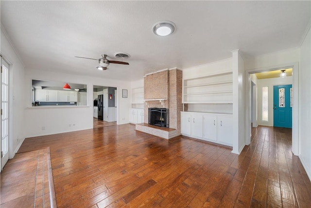 unfurnished living room featuring visible vents, baseboards, a brick fireplace, a ceiling fan, and hardwood / wood-style floors