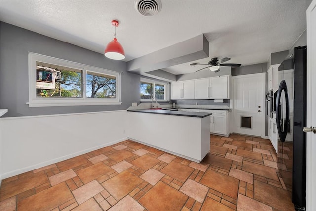 kitchen with decorative light fixtures, ceiling fan, black fridge, kitchen peninsula, and white cabinets