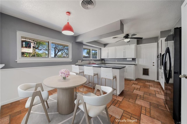 dining area with ceiling fan, sink, and a textured ceiling