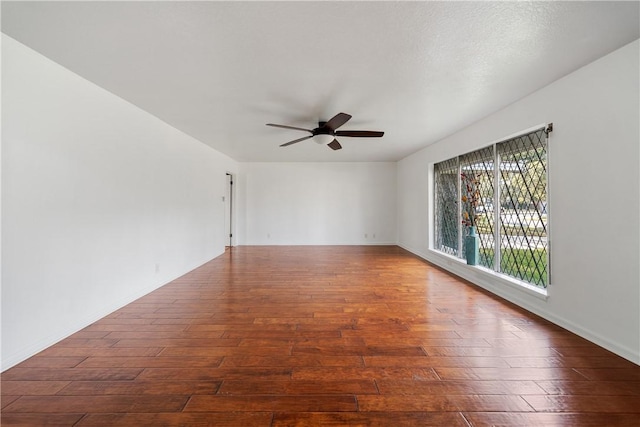 empty room with ceiling fan and dark hardwood / wood-style flooring