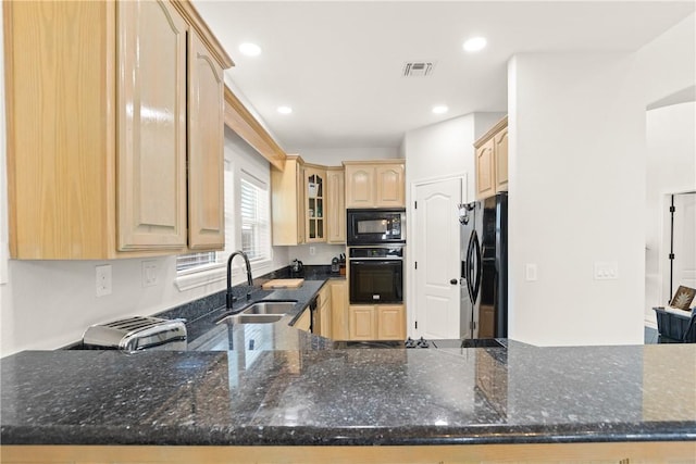 650 S Bay St, Aransas Pass, TX 78336 - kitchen with black appliances, light brown cabinetry, dark stone countertops, glass insert cabinets, and recessed lighting