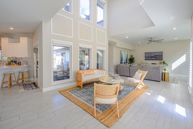 living room featuring a towering ceiling, a wealth of natural light, and light hardwood / wood-style flooring