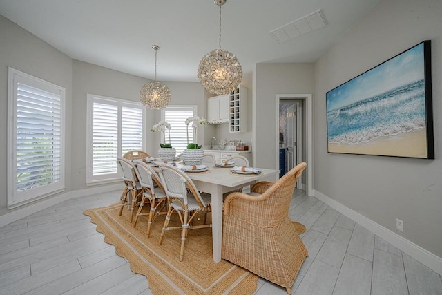 dining room with sink, light wood-type flooring, and an inviting chandelier