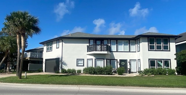 view of front of house with a garage, a front yard, and a balcony