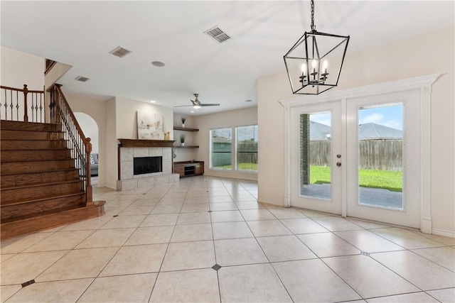 6530 Picante Dr, Corpus Christi, TX 78414 - unfurnished living room with french doors, stairway, a tile fireplace, ceiling fan, and light tile patterned floors