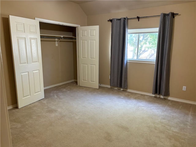 unfurnished bedroom featuring light colored carpet, lofted ceiling, and a closet