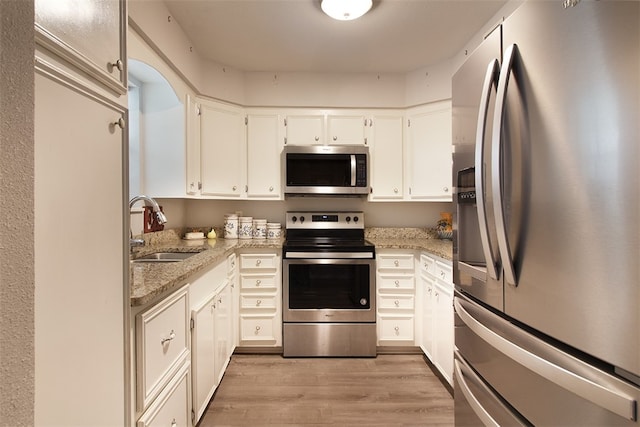 4445 Cedar Pass Dr Unit 103, Corpus Christi, TX 78413 - kitchen with stainless steel appliances, light wood-type flooring, light stone countertops, and white cabinetry