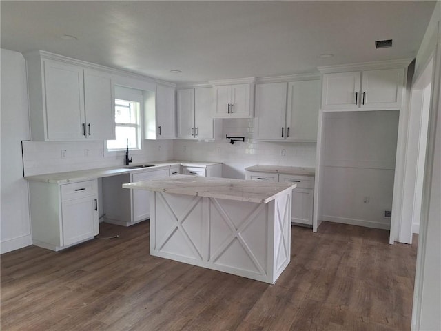 kitchen featuring white cabinetry, decorative backsplash, a sink, and wood finished floors
