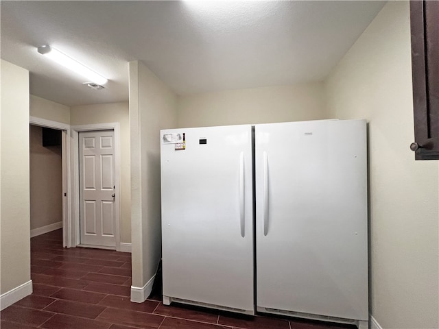 kitchen with white fridge and dark wood-type flooring