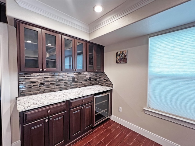 bar with tasteful backsplash, dark brown cabinets, dark wood-type flooring, crown molding, and wine cooler