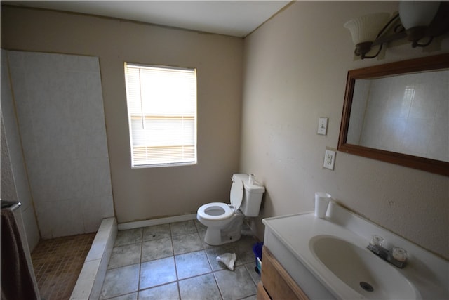 bathroom featuring toilet, vanity, tile patterned flooring, and a tile shower