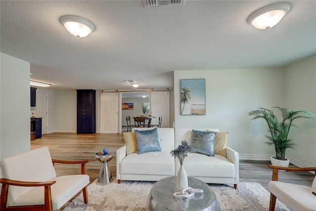 living room with a textured ceiling, light hardwood / wood-style floors, and a barn door