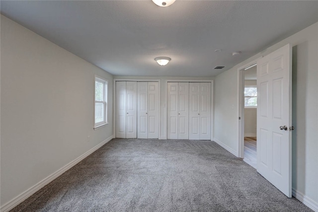 unfurnished bedroom with multiple closets and carpet flooring