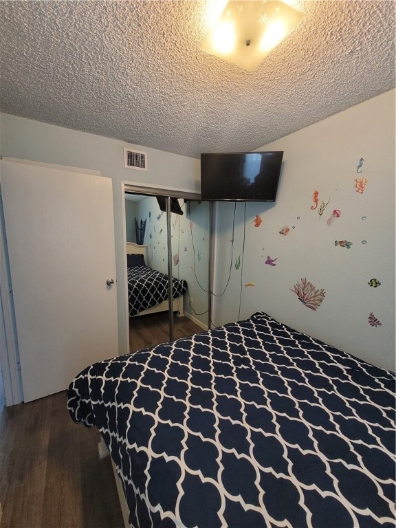 bedroom featuring hardwood / wood-style flooring, a textured ceiling, and a closet