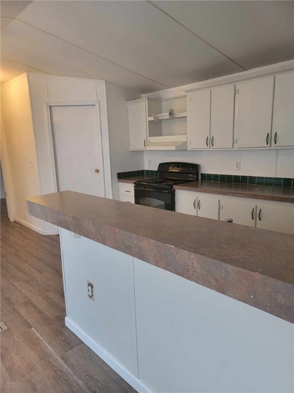 kitchen with black electric range, white cabinets, and hardwood / wood-style flooring