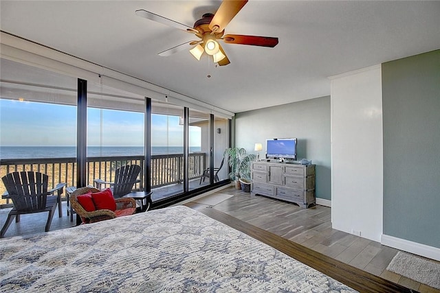 bedroom with access to exterior, ceiling fan, a wall of windows, light hardwood / wood-style flooring, and a water view