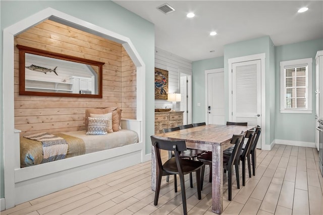 dining room with light hardwood / wood-style flooring and wooden walls