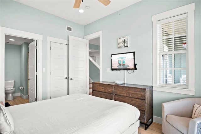 bedroom featuring a closet, light wood-type flooring, connected bathroom, and ceiling fan