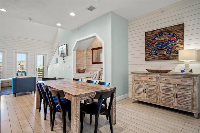 dining space featuring wood walls and vaulted ceiling