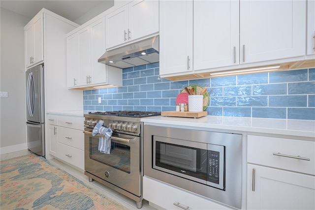 kitchen with light countertops, backsplash, appliances with stainless steel finishes, white cabinets, and under cabinet range hood